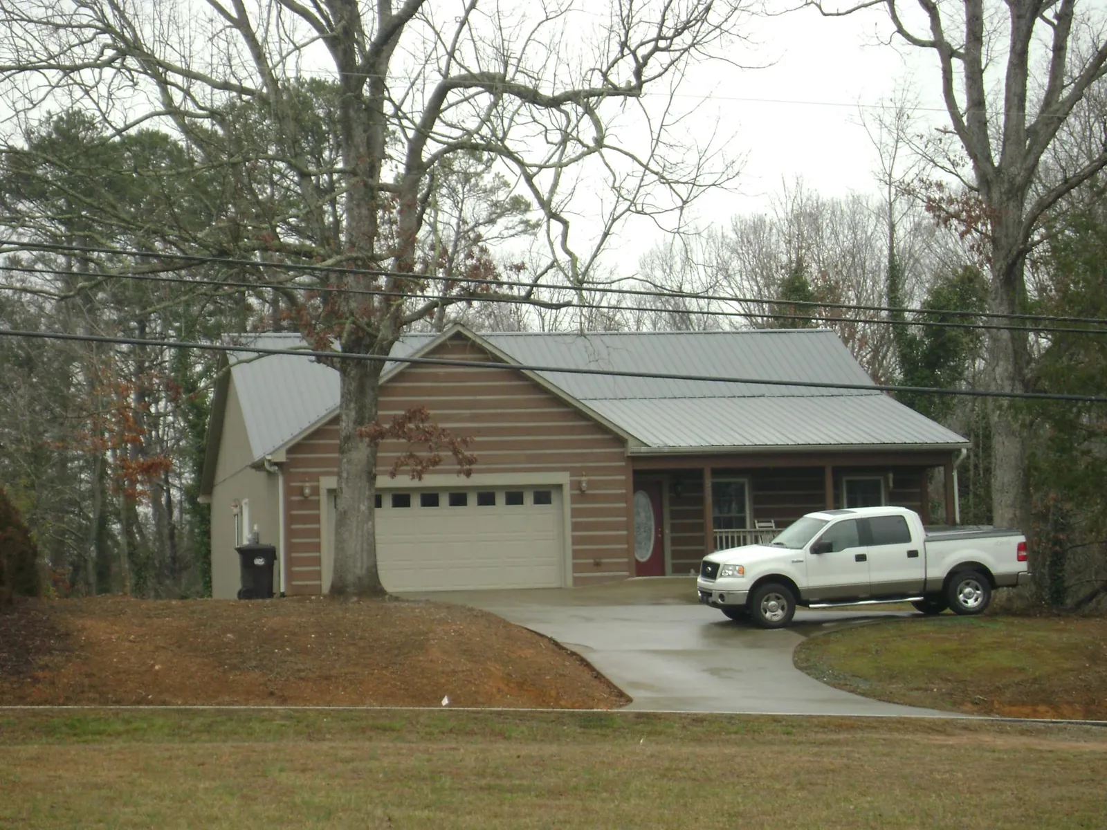Gray metal roof on a log sided house with an attached two car garage in Greenville